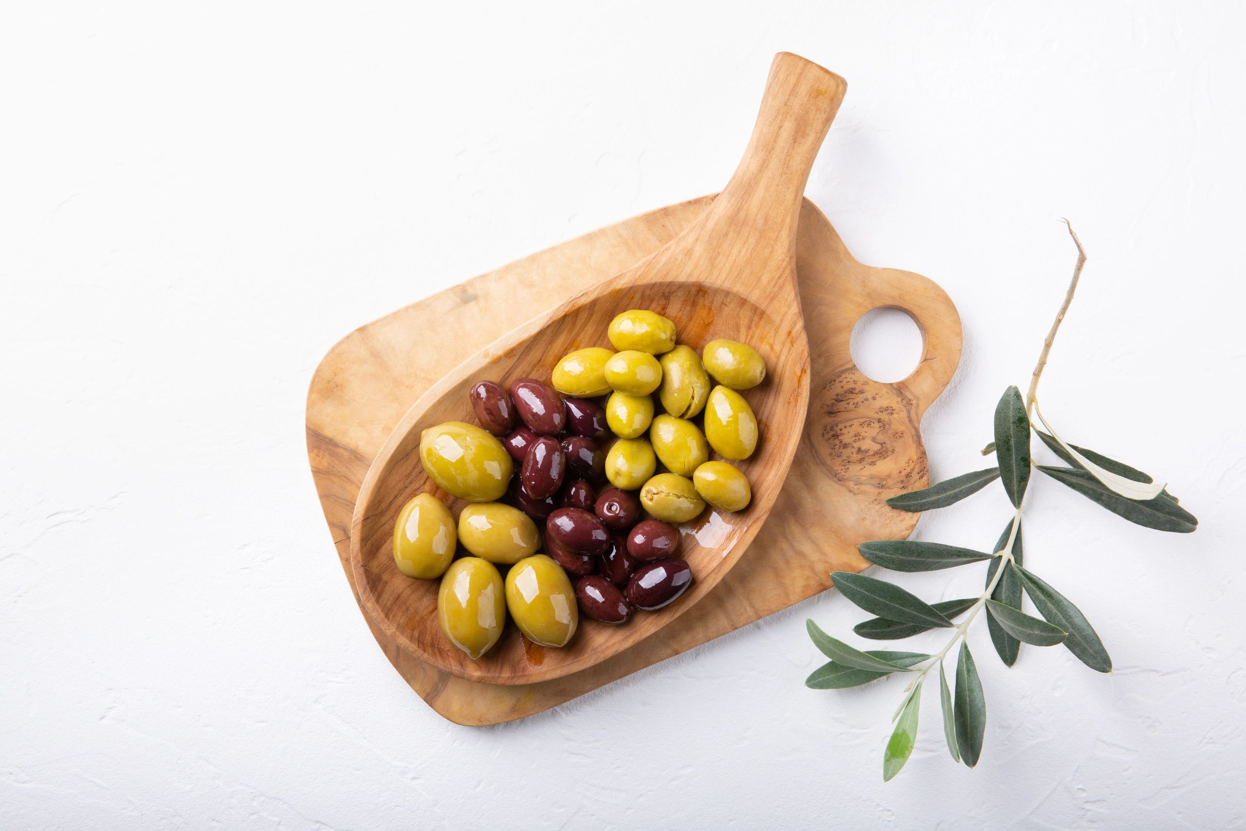 Top view of green and black olives on a wooden plate