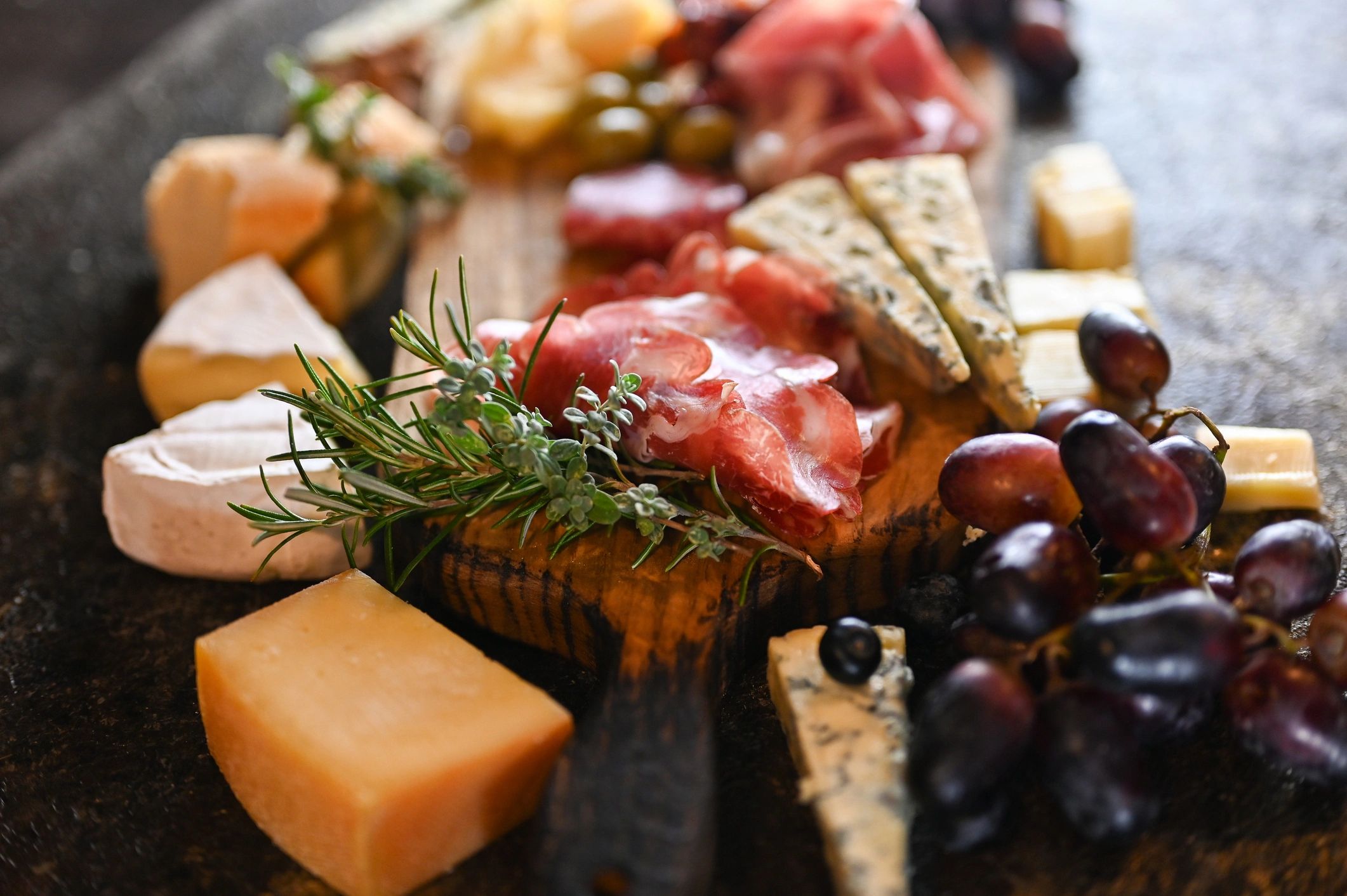 Charcuterie board with cheeses, grapes, and cured meats