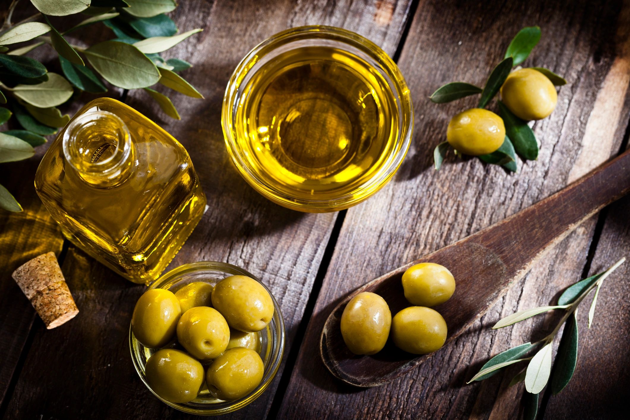 Olive oil and green olives on rustic table